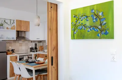 a kitchen with a table and chairs and a painting at Bluebell House Halki in Halki