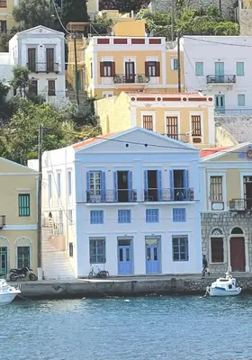 a white building on the water next to buildings at Anamar Symi Residences in Symi