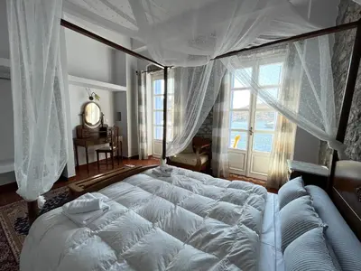a bedroom with a large white bed with a window at Anamar Symi Residences in Symi