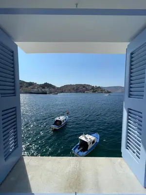 two boats on a body of water in a room at Anamar Symi Residences in Symi