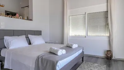 a white bedroom with a bed and a window at Blue Heaven Kerami in Archangelos
