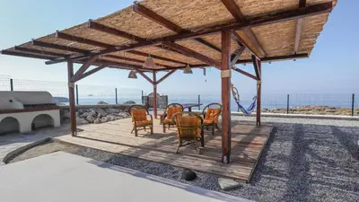 a pavilion with chairs and a table and the ocean at Blue Heaven Kerami in Archangelos