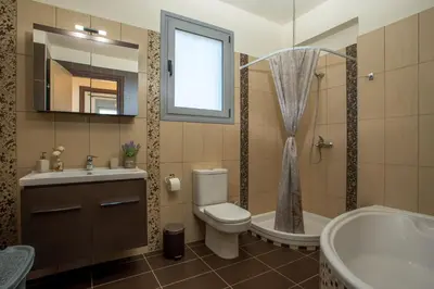 a bathroom with a toilet and a sink and a tub at Captain Chris Villa in Afantou