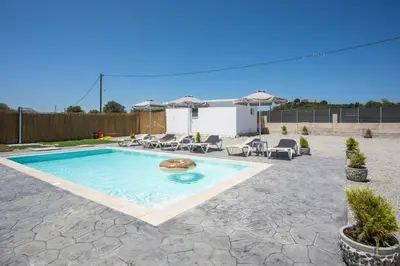 a swimming pool in a yard with chairs and umbrellas at Captain Chris Villa in Afantou