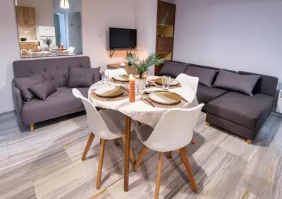 a dining room table with white chairs and a couch at Anali Apartment in Ixia