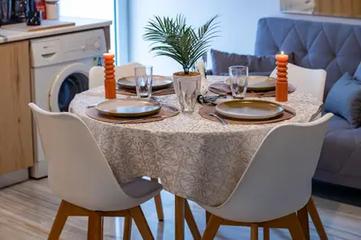 a dining room table with white chairs and a table with plates and candles at Anali Apartment in Ixia