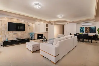 a living room with white furniture and a stone wall at Amarilia House in Koskinou