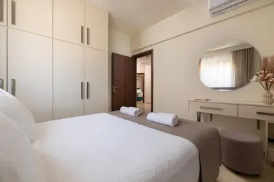 a bedroom with a large white bed and a mirror at Amarilia House in Koskinou