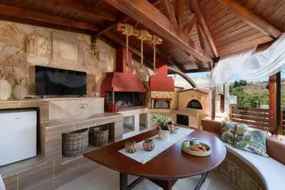 a living room with a table and a fireplace at Amarilia House in Koskinou