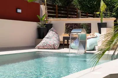 a woman laying on a couch next to a swimming pool at Amarilia House in Koskinou