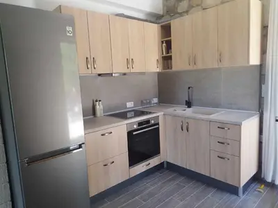 a kitchen with wooden cabinets and a stainless steel refrigerator at Tropical Garden Faliraki Rhodes in Faliraki