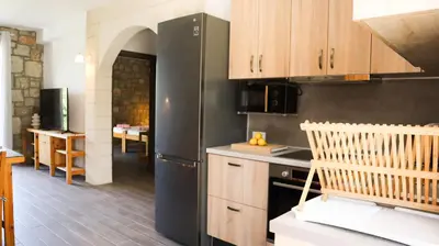 a kitchen with a black refrigerator and wooden cabinets at Tropical Garden Faliraki Rhodes in Faliraki