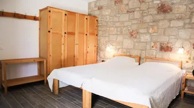 a bedroom with a white bed and a stone wall at Tropical Garden Faliraki Rhodes in Faliraki