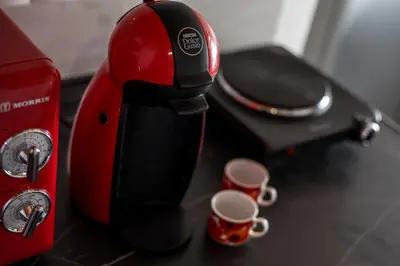 a red and black coffee maker with two cups on a counter at Marco Beach Tiny House in Faliraki