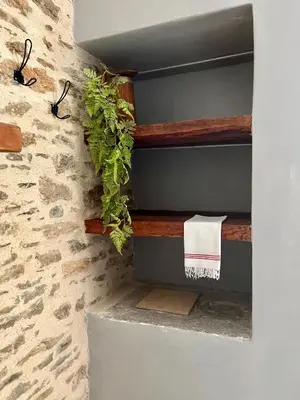 a bathroom with wooden shelves and a stone wall at Katrani studios in Symi