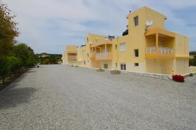 a row of yellow buildings on a gravel road at Treditto House - Ground Floor residence C1 in Koskinou
