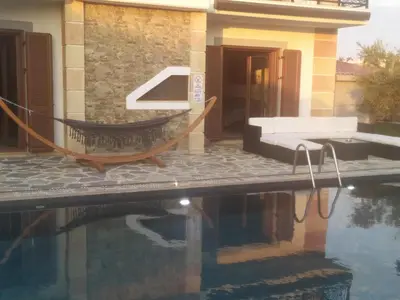 a hammock in front of a house with a swimming pool at Sun Dream Villa in Ialyssos