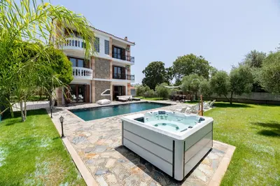 a hot tub in a yard next to a house at Sun Dream Villa in Ialyssos