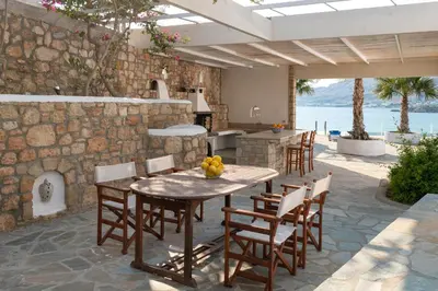 a patio with a table and chairs and a stone wall at Arte Pefki Beachfront Suites in Pefki Rhodes