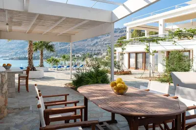 a wooden table with a bowl of fruit on a patio at Arte Pefki Beachfront Suites in Pefki Rhodes