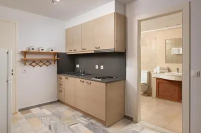 a kitchen with wooden cabinets and a sink at Arte Pefki Beachfront Suites in Pefki Rhodes