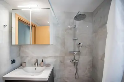 a bathroom with a sink and a shower with a mirror at Eramel Cozy Apartment with Sea View in Rhodes Town