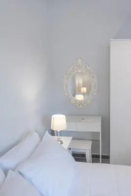 a white bedroom with a bed and a mirror at Eramel Cozy Apartment with Sea View in Rhodes Town