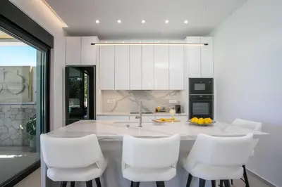a kitchen with white chairs and a kitchen island at Ocean Pearl Sea View in Faliraki