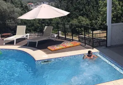 a man in a swimming pool with an umbrella at villa Aphrodite Rhodes in Pastida