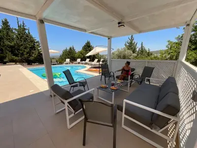 a man sitting on a patio under a white pergola at villa Aphrodite Rhodes in Pastida