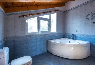 a bathroom with a tub and a toilet and a window at villa Aphrodite Rhodes in Pastida