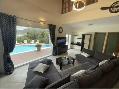 a living room with a couch and a tv and a pool at villa Aphrodite Rhodes in Pastida