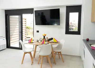 a dining room with a wooden table and white chairs at Wohlfühloase 1 Casa Elena und Gerd in Rhodes Town