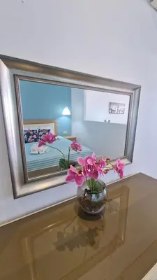 a vase with flowers on a table in front of a mirror at Studio Mare Faliraki in Faliraki