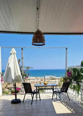 a patio with a table and chairs and the beach at Studio Mare Faliraki in Faliraki