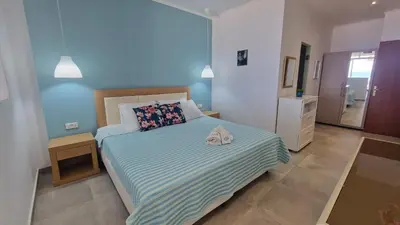 a bedroom with a bed with a blue wall at Studio Mare Faliraki in Faliraki