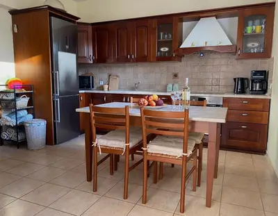 a kitchen with a table with chairs and a refrigerator at Villa Sofia with garden, pool and lounge areas in Kolimbia