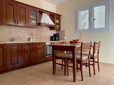 a kitchen with a wooden table and chairs and a sink at Villa Sofia with garden, pool and lounge areas in Kolimbia