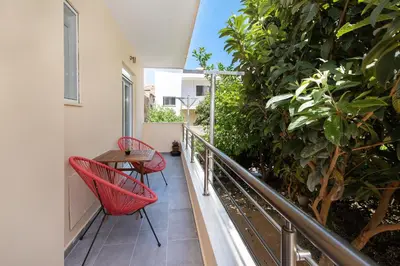 a balcony with two red chairs and a table at Casa di Calma & Casa di Luce Rhodes Apartments in Rhodes Town