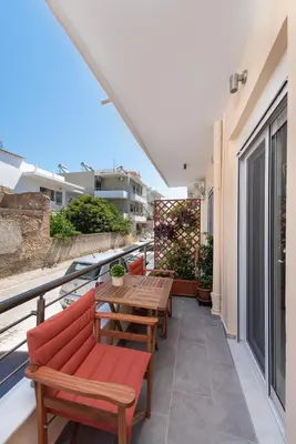 a patio with wooden tables and chairs on a balcony at Casa di Calma & Casa di Luce Rhodes Apartments in Rhodes Town