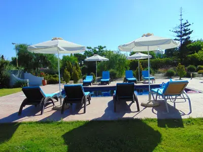 a group of chairs and tables with umbrellas at Villa Dora in Faliraki