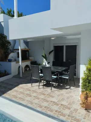 a patio with a table and chairs next to a pool at Platanos Villa in Haraki