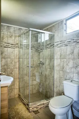 a bathroom with a shower with a toilet and a sink at Platanos Villa in Haraki