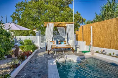 a backyard with a pool with a swing and a bed at Platanos Villa in Haraki