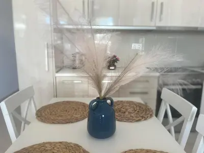 a table with a blue vase with a plant in it at Nesèa Apartment Faliraki in Faliraki