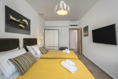 a bedroom with two beds and a flat screen tv at Nice n Cosy Apartment I in Rhodes Town