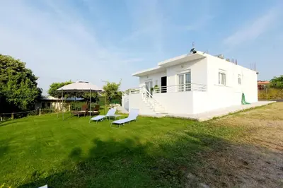 a white house with chairs and an umbrella at Emerald Private Villa in Kalavarda Rhodes in Kalavárda