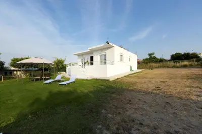a small white house with two chairs and an umbrella at Emerald Private Villa in Kalavarda Rhodes in Kalavárda