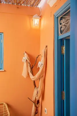 a room with an orange wall with a dried flower on the wall at SUN PETRADI Tradition & Luxury in Koskinou