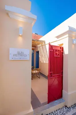 a red door in a building with a sign on it at SUN PETRADI Tradition & Luxury in Koskinou